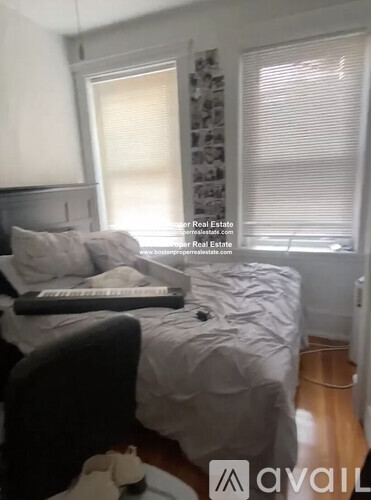 A bedroom with a bed, pillows, and a window with blinds.