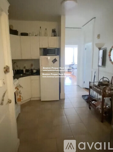 A kitchen with white cabinets and a refrigerator.