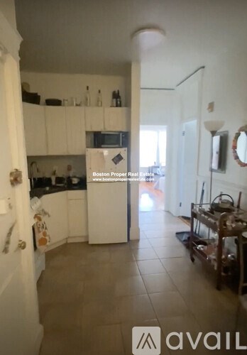 A kitchen with white cabinets and a refrigerator.