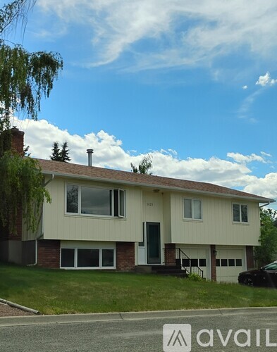A two-story house with a white exterior and a black car parked in front.