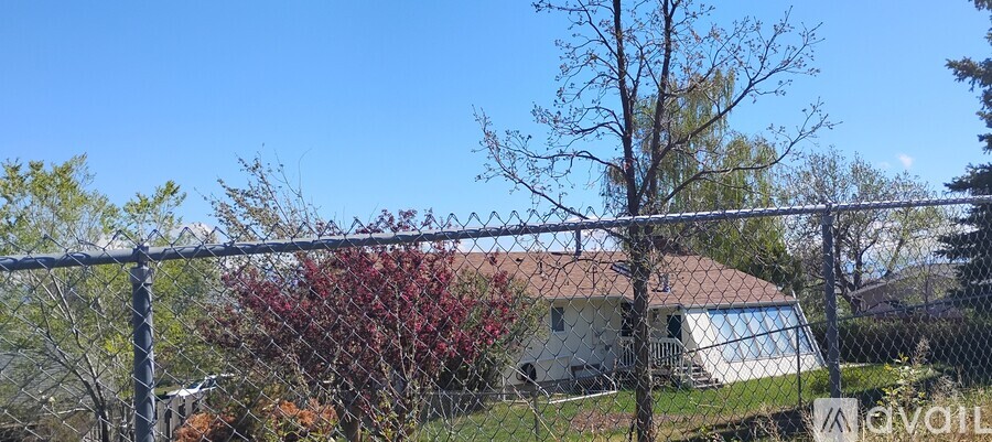 A house is behind a fence with a sign that says "available".