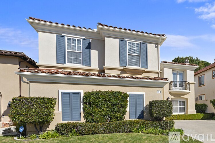 A two-story house with a balcony and blue shutters.