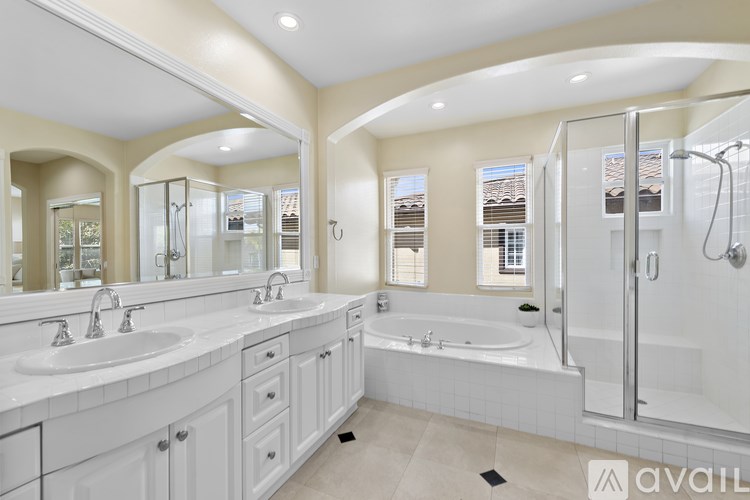 A bathroom with a large tub and double sinks.