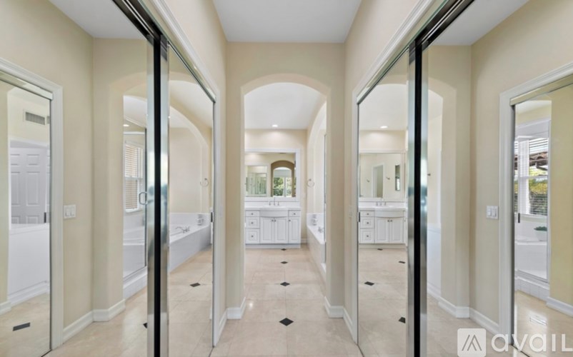 A hallway with mirrors on both sides leading to a kitchen.