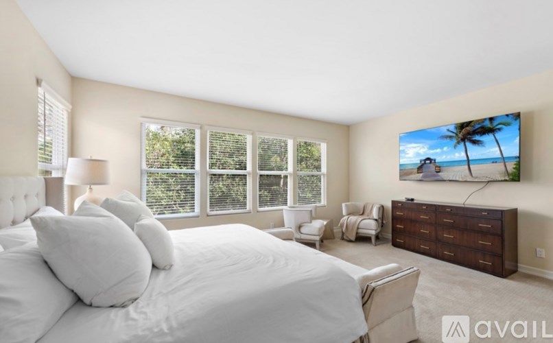 A bedroom with a large bed and a television displaying a beach scene.