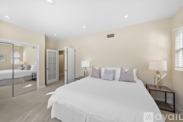 A bedroom with a large bed and a glass door leading to another room.
