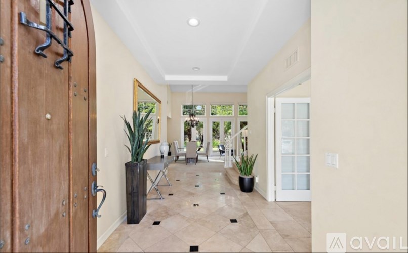 A hallway with a wooden door and a plant on the floor.