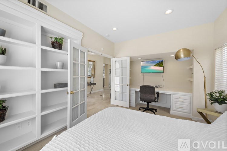 A bedroom with a large bed, a desk with a chair, and a cabinet with shelves.
