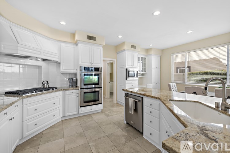 A kitchen with white cabinets and a granite countertop.