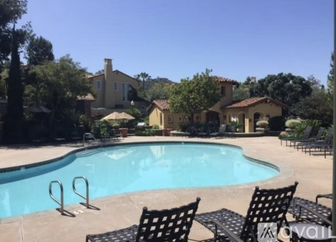 A pool with chairs around it and a house in the background.