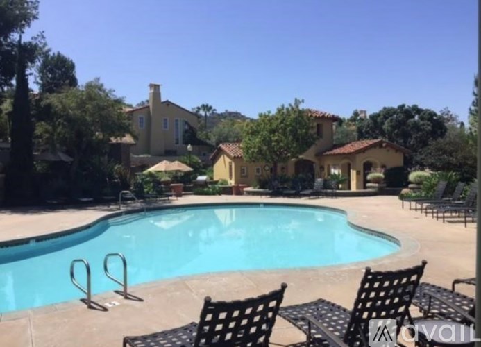 A pool with chairs around it and a house in the background.