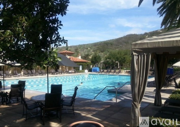 A pool surrounded by chairs and trees.