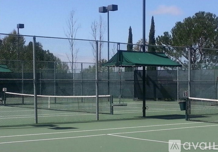 Tennis court with a fence and a green roof.