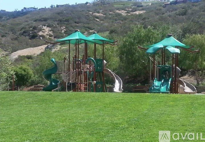 A playground with a green slide and a wooden structure.