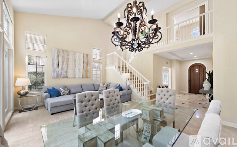 A living room with a grey sofa, a glass coffee table, and a chandelier.
