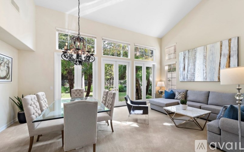 A living room with a grey sofa, glass table, and a chandelier.