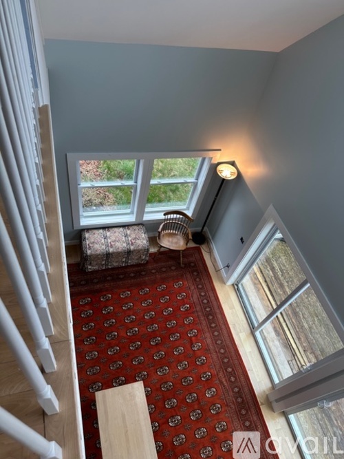 A red carpeted stairway leads to a balcony with a view of trees.