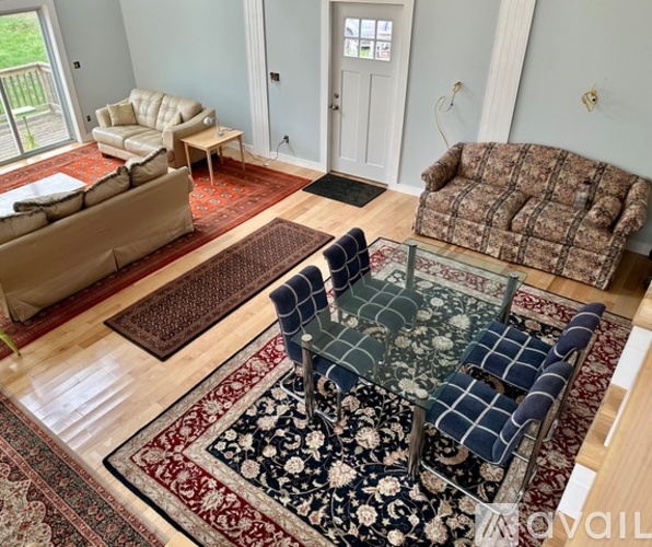 A living room with a rug and a glass table.