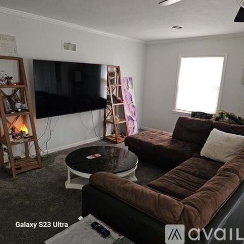 A living room with a brown couch, a flat screen TV, and a coffee table.