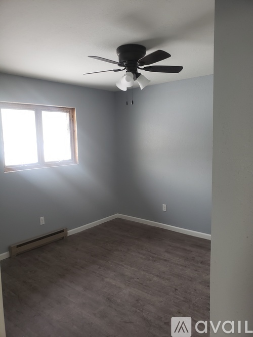 A room with a ceiling fan and a window letting in sunlight.