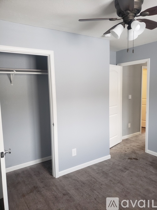 A room with a ceiling fan and a doorway leading to another room.