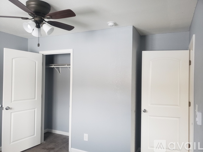 A room with a ceiling fan and two doors.