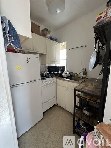 A kitchen with a white refrigerator and white cabinets.