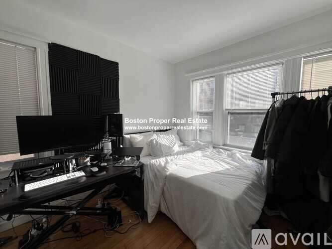 A bedroom with a bed, desk, and clothing rack.