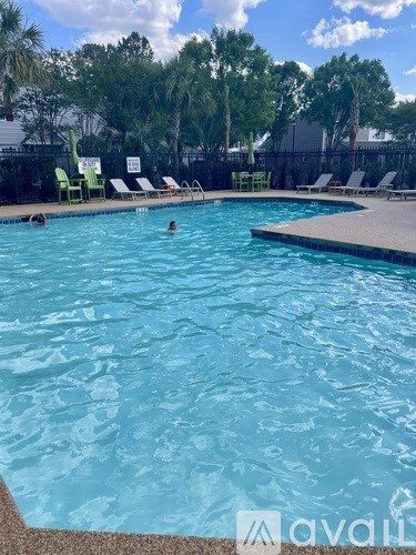 A pool with people swimming in it and chairs around it.