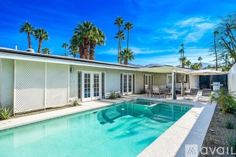A pool in front of a house with palm trees in the background.