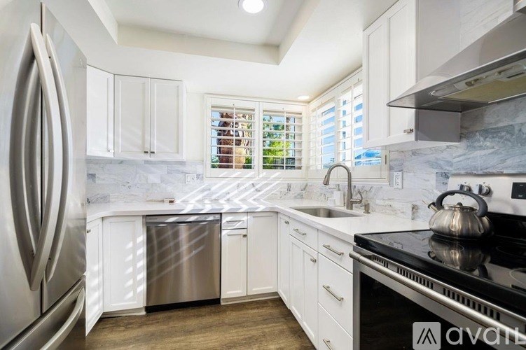 A kitchen with white cabinets and a stainless steel refrigerator.