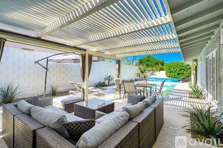 A patio with a white couch and a glass table.
