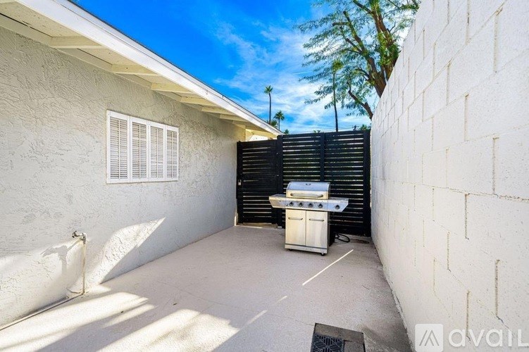 A patio with a grill and a wall on one side.