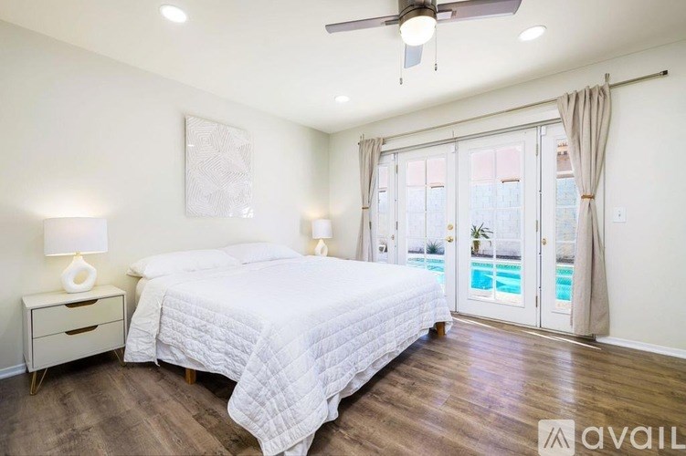 A bedroom with a large bed and a view of a pool through the sliding glass doors.