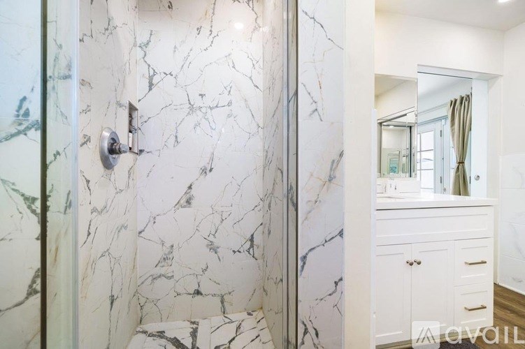 A bathroom with a marble wall and a white vanity.