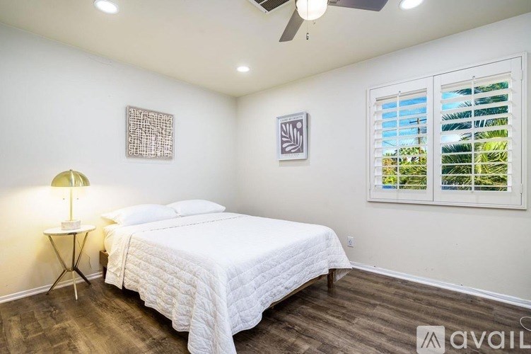 A bedroom with a bed, a lamp, and two pictures on the wall.