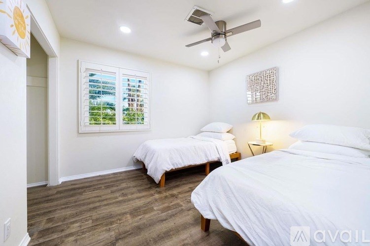 A bedroom with two beds and a ceiling fan.