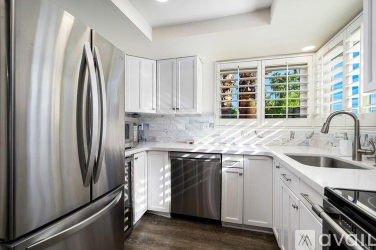A modern kitchen with a stainless steel refrigerator and white cabinets.