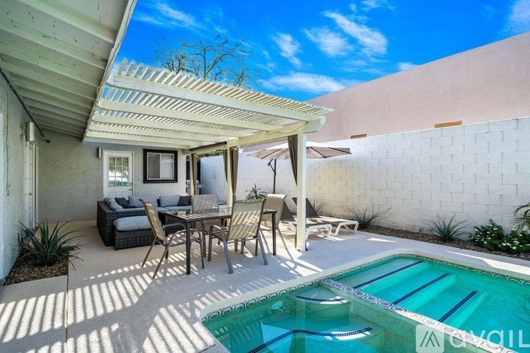 A patio with a table and chairs is shaded by a white awning.