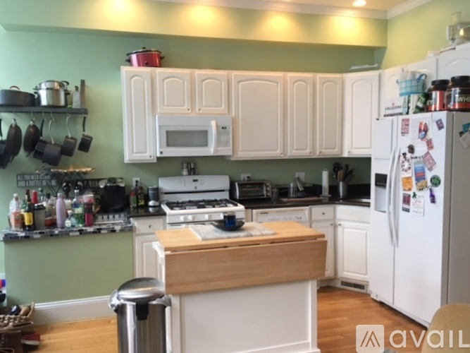 A kitchen with white cabinets and a wooden island.