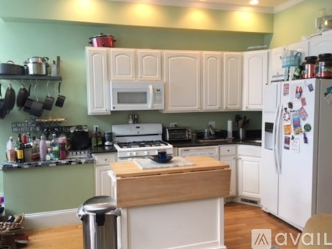 A kitchen with white cabinets and a wooden island.