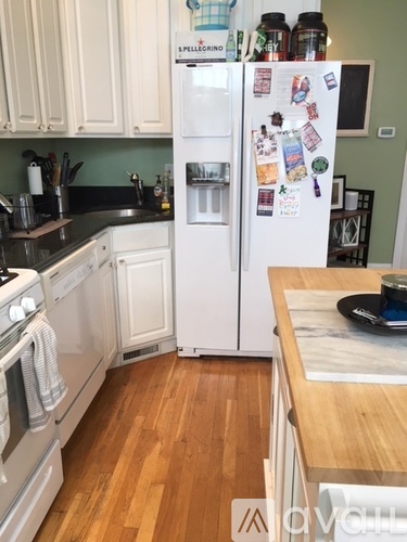 A kitchen with a white fridge and wooden floors.