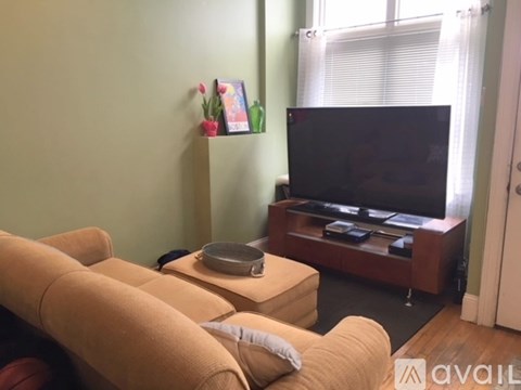 A living room with a tan couch and a black television.
