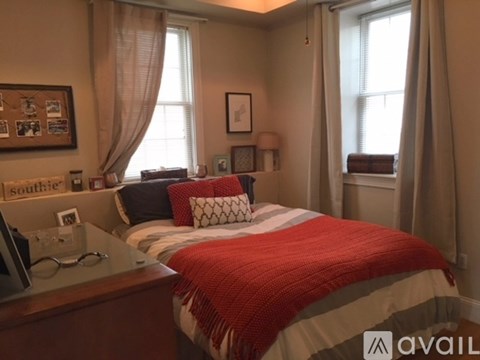 A bedroom with a bed covered in a red and white comforter.
