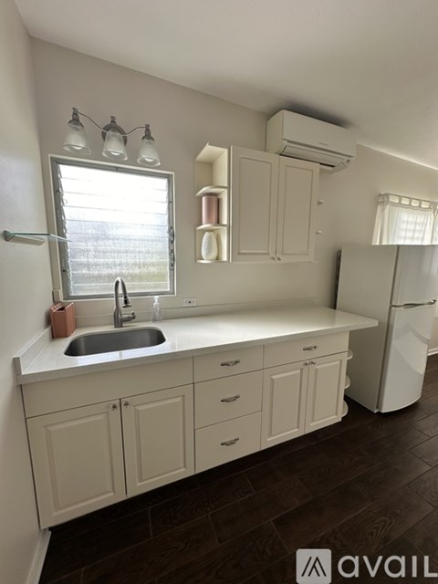 A kitchen with white cabinets and a wooden floor.