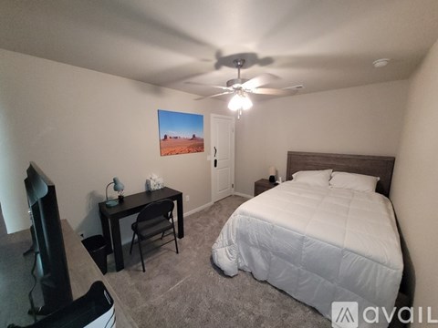 A bedroom with a bed, desk, and chair.