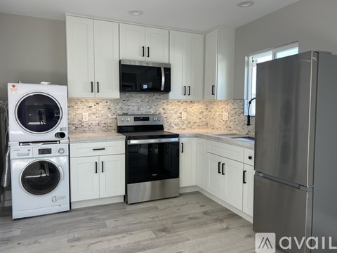 A modern kitchen with white cabinets and stainless steel appliances.