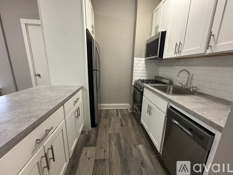 A kitchen with white cabinets and a wooden floor.