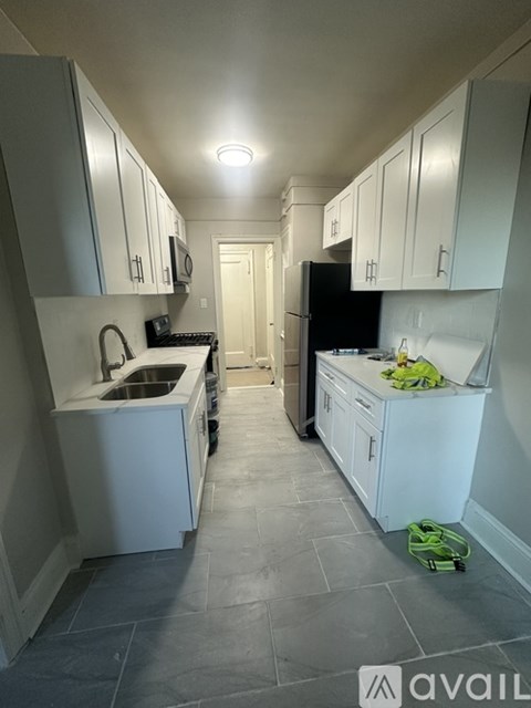 A kitchen with white cabinets and a black fridge.