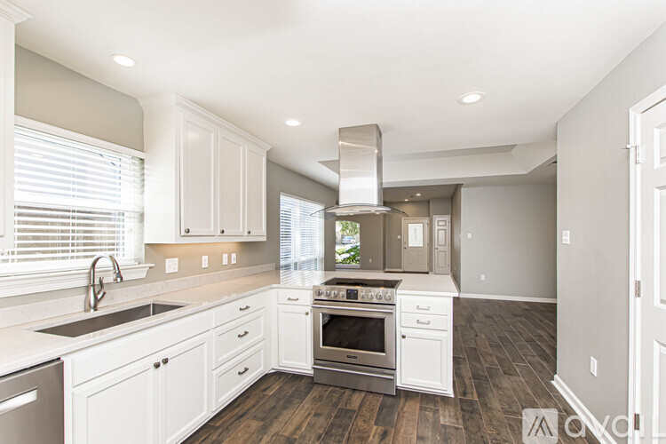 A modern kitchen with white cabinets and stainless steel appliances.